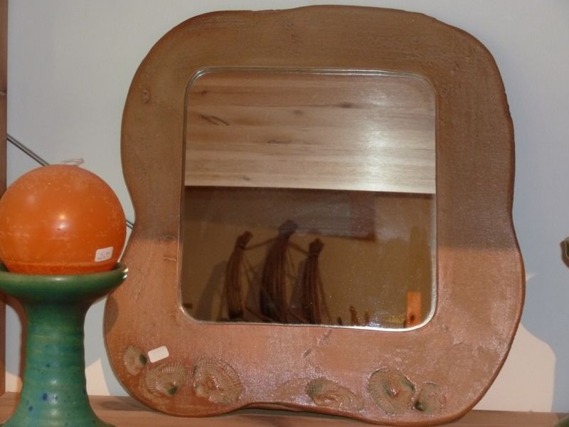 Ein Holzspiegel steht auf einem Tisch neben einer Kerze