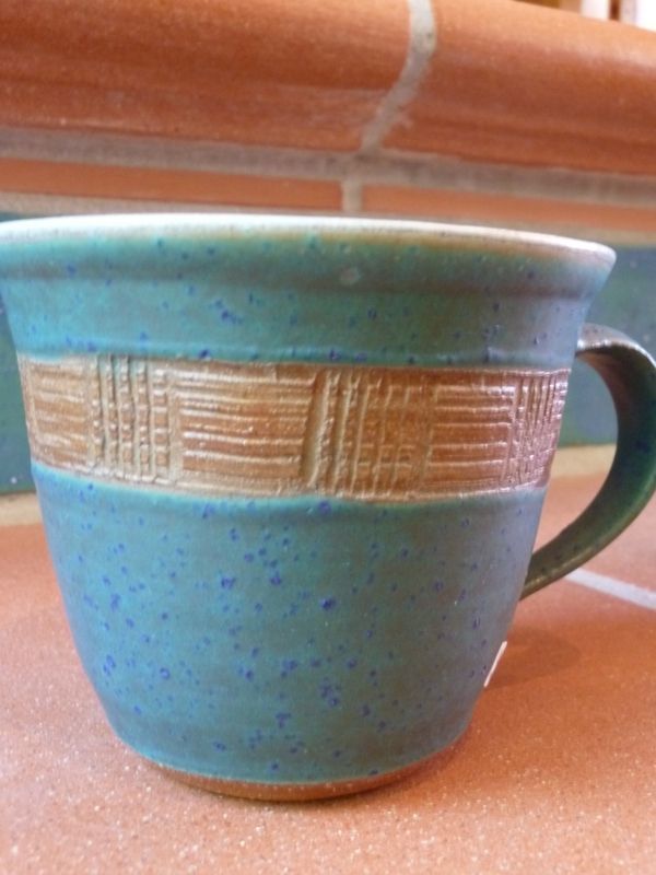 Eine blaue Tasse mit Henkel steht auf einem Tisch