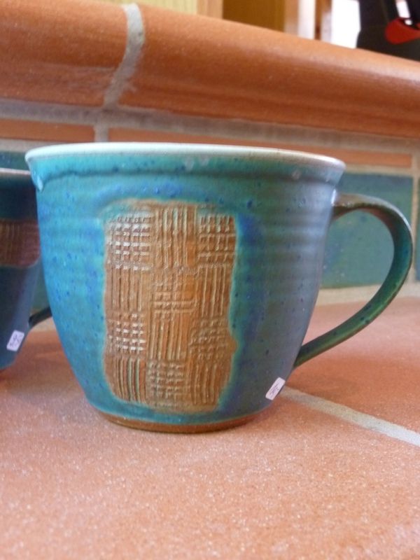 Eine blaue Tasse mit einem Muster darauf steht auf einem Tisch