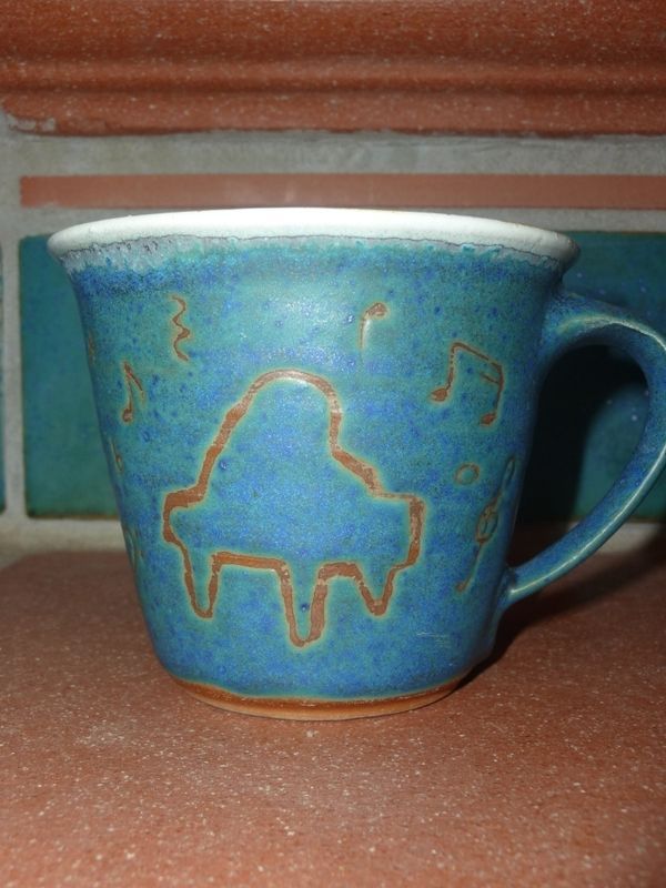 Eine blaue Tasse mit einem Klavier und Musiknoten darauf