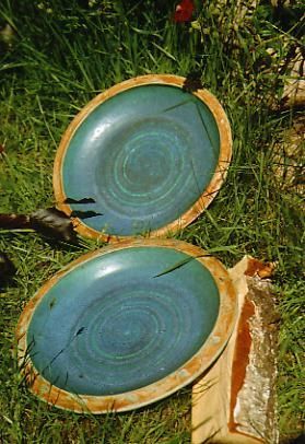 Zwei Teller liegen übereinander im Gras.