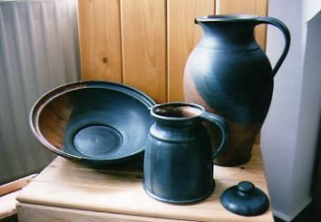 Ein Krug, eine Schüssel und eine Tasse stehen auf einem Holztisch.