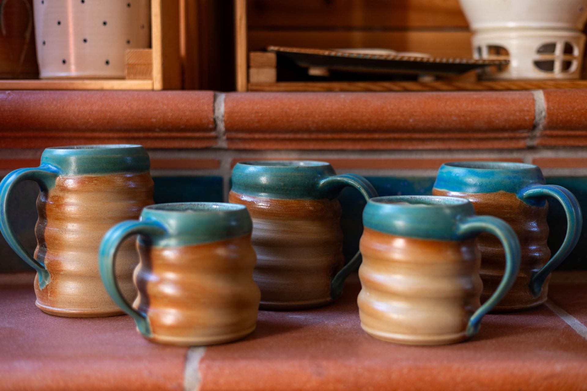 Auf einem gemauerten Regal stehen vier Kaffeetassen.