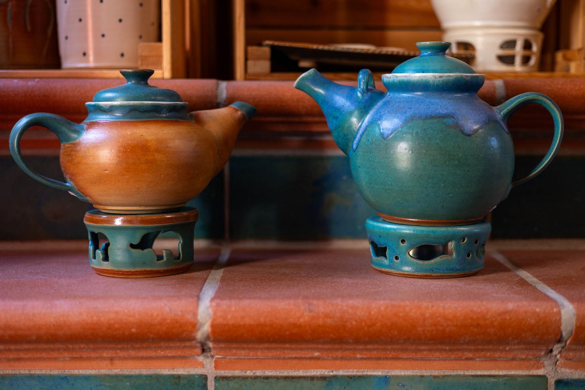 Zwei Teekannen stehen auf einer gefliesten Arbeitsplatte.