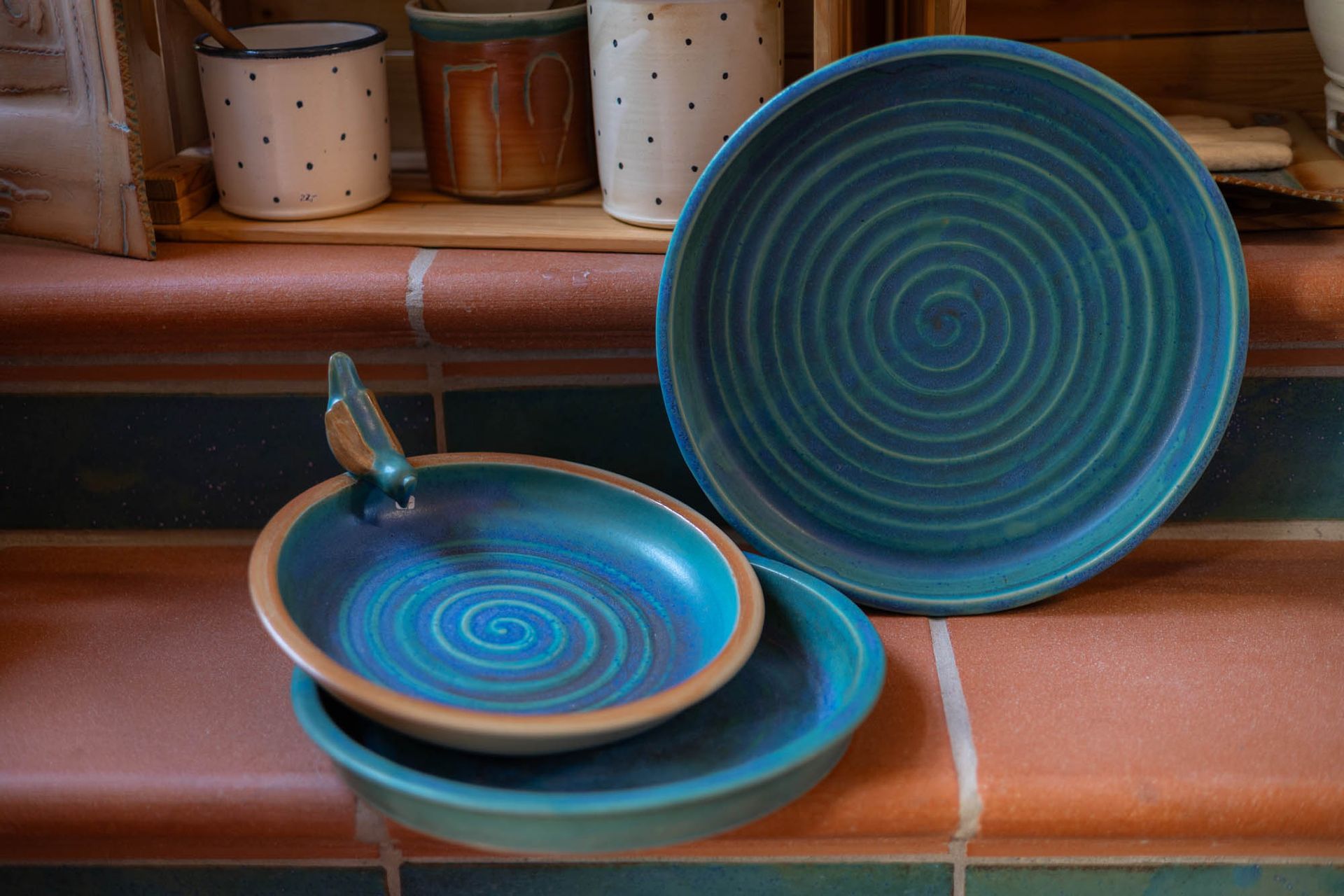 Drei blaue Teller stehen auf einem gefliesten Boden.