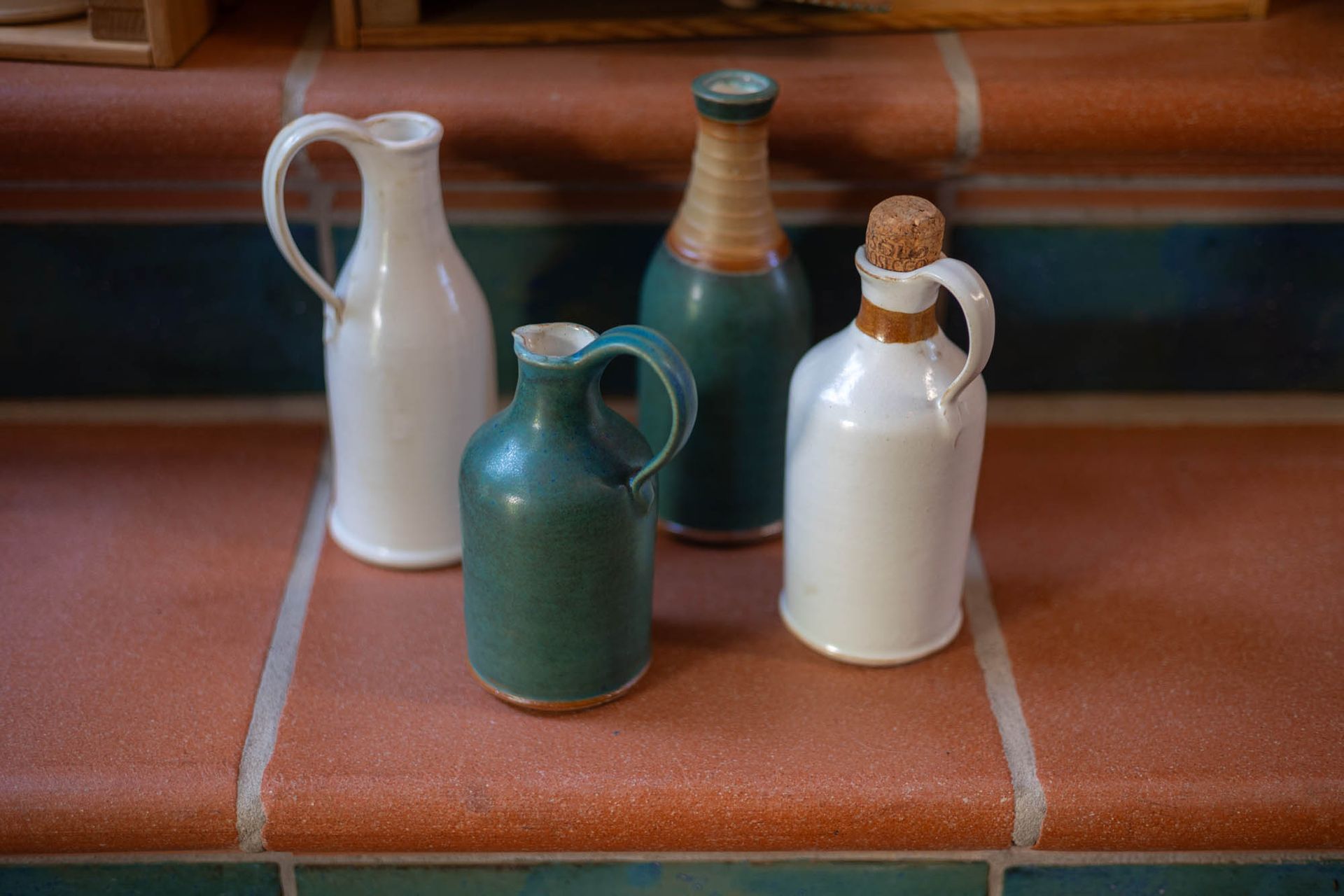 Vier Keramikvasen stehen auf einem gefliesten Boden.