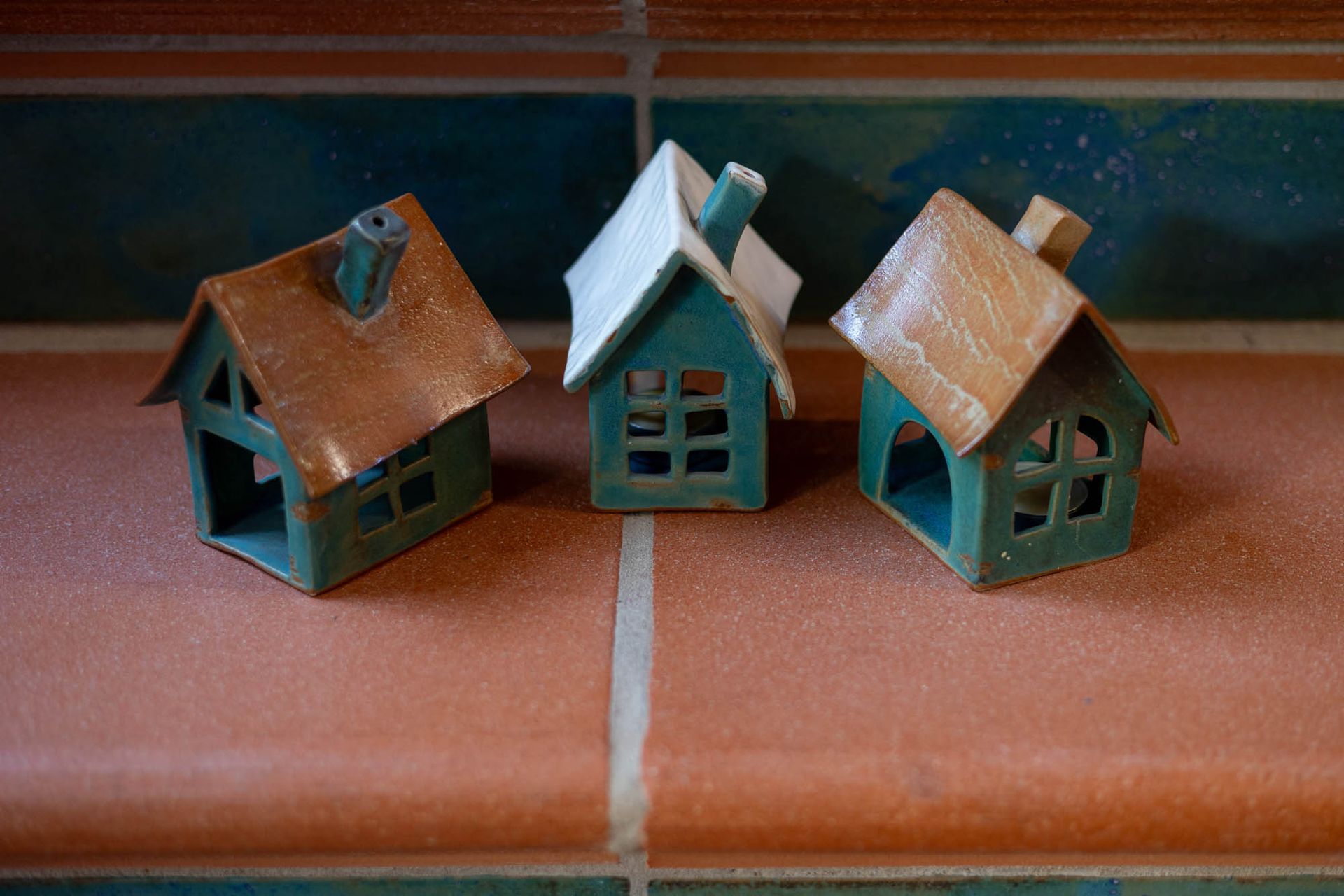 Drei kleine Häuser stehen auf einem gefliesten Regal.