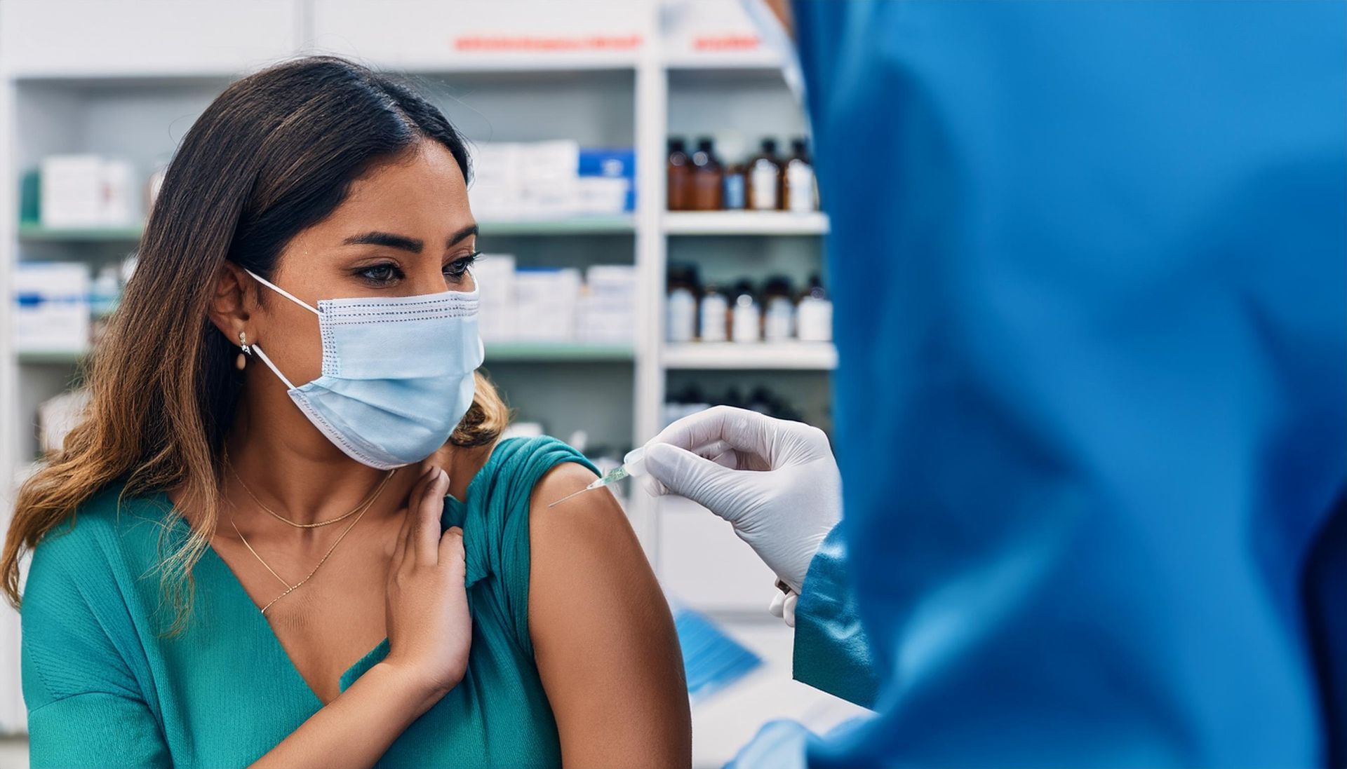 Un patient masqué reçoit une injection de vaccin dans une pharmacie.