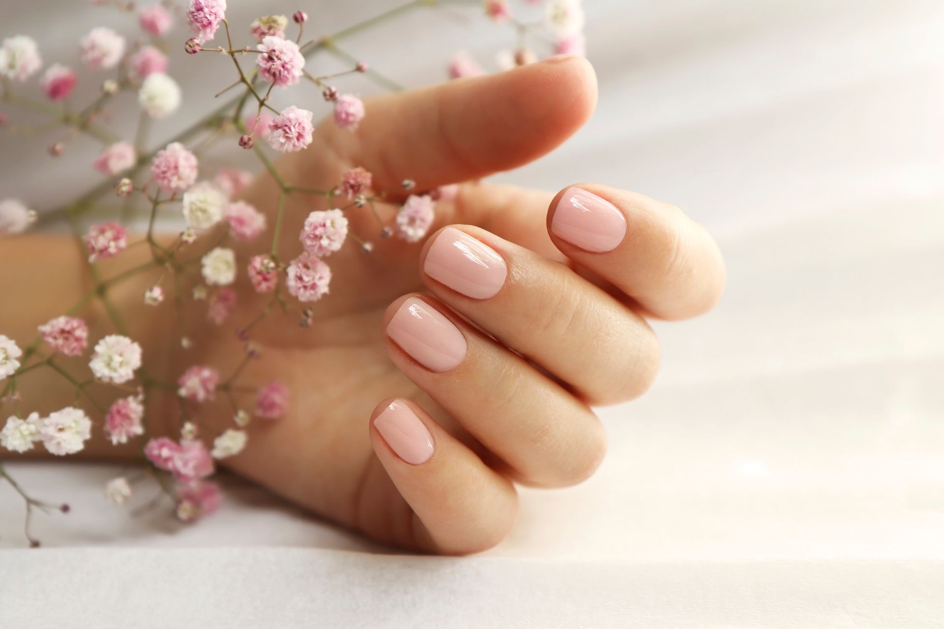 Hände bei der Maniküre, Nagelfeile im Einsatz, Salon-Atmosphäre.