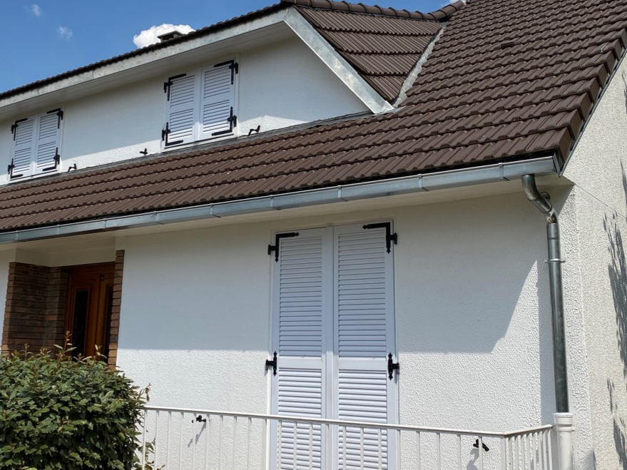 Façade d'une maison avec une gouttière en zinc et une descente d'eau.