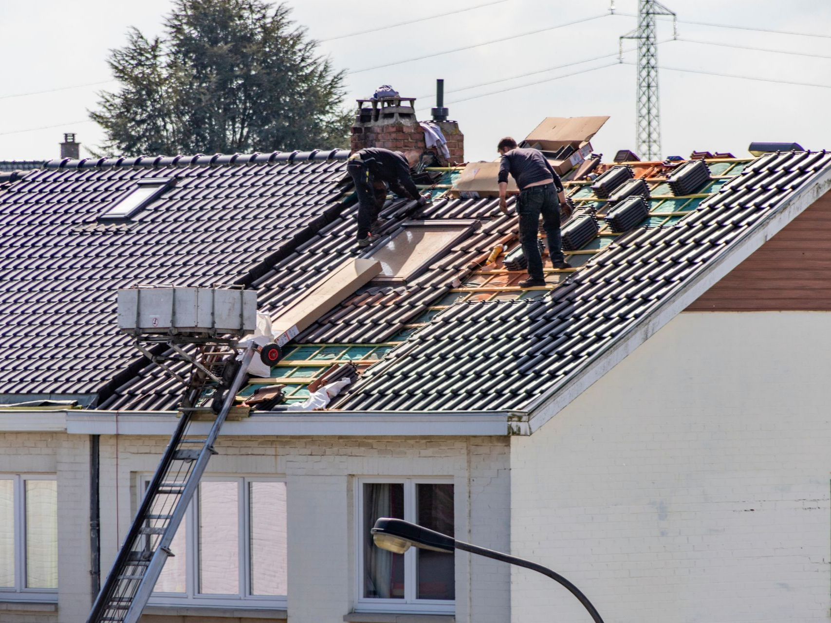 Deux professionnels sur le toit en train de poser les tuiles.
