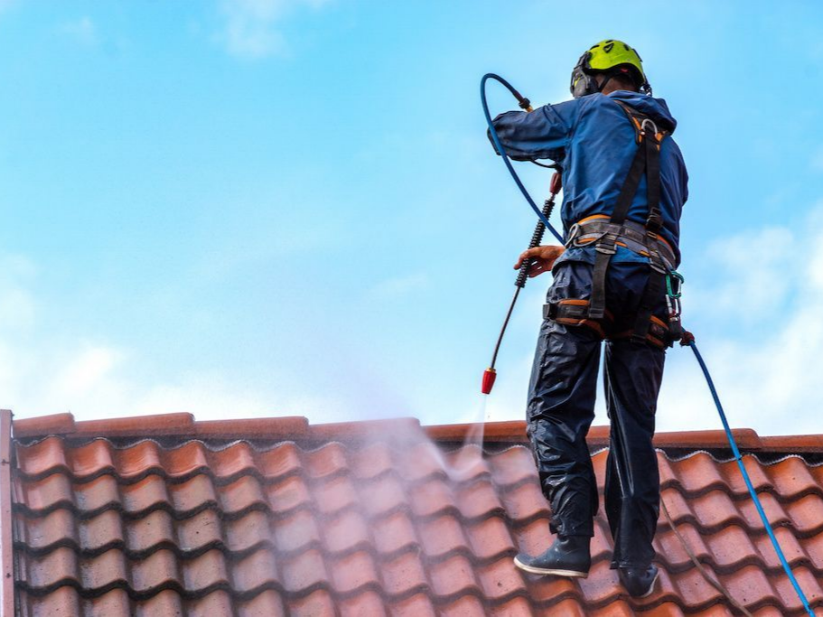 Professionnel de toiture en train de nettoyer les tuiles à haute pression.