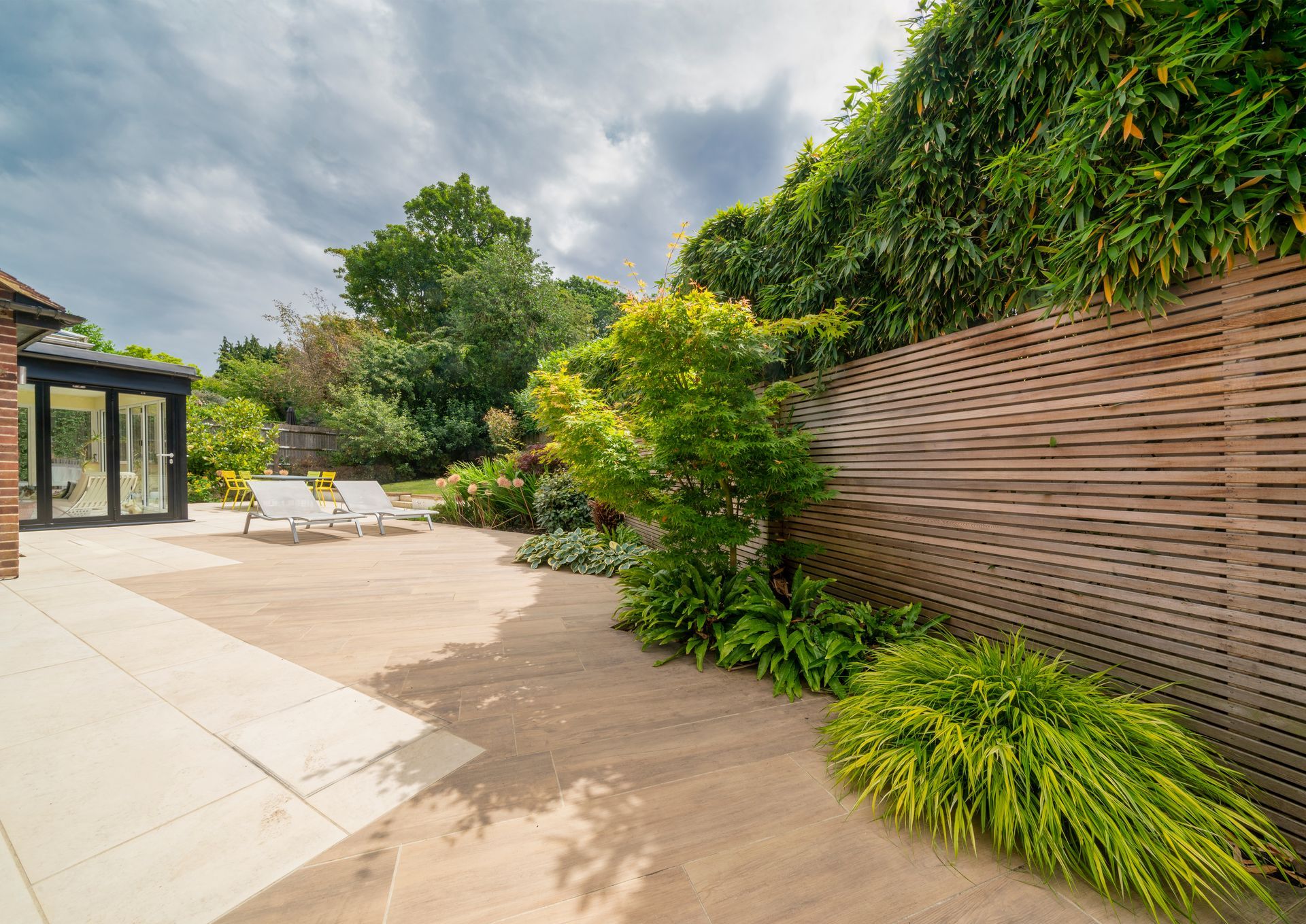 Eine Terrasse mit Stühlen und einem Holzzaun in einem Garten.
