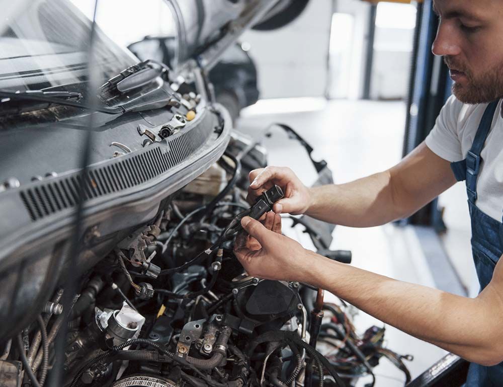 Un hombre está trabajando en el motor de un coche en un garaje.