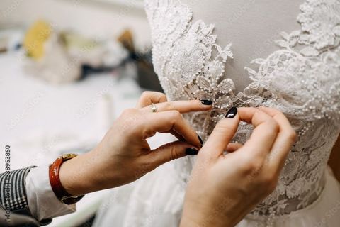 Une femme prépare une robe de mariée pour une mariée.