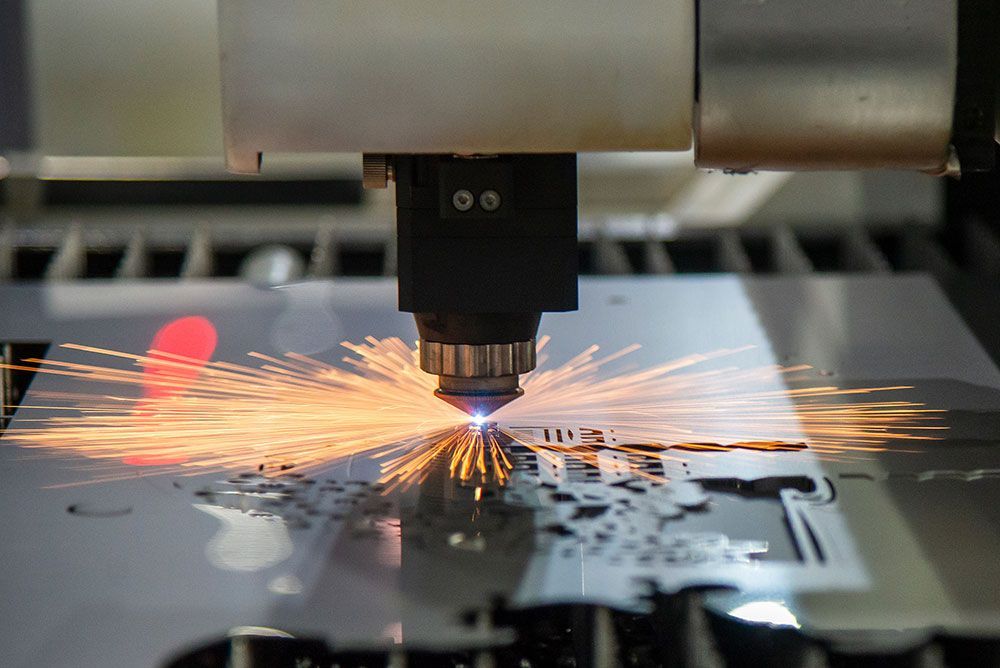 Eine Maschine schneidet ein Stück Metall, wobei Funken entstehen.