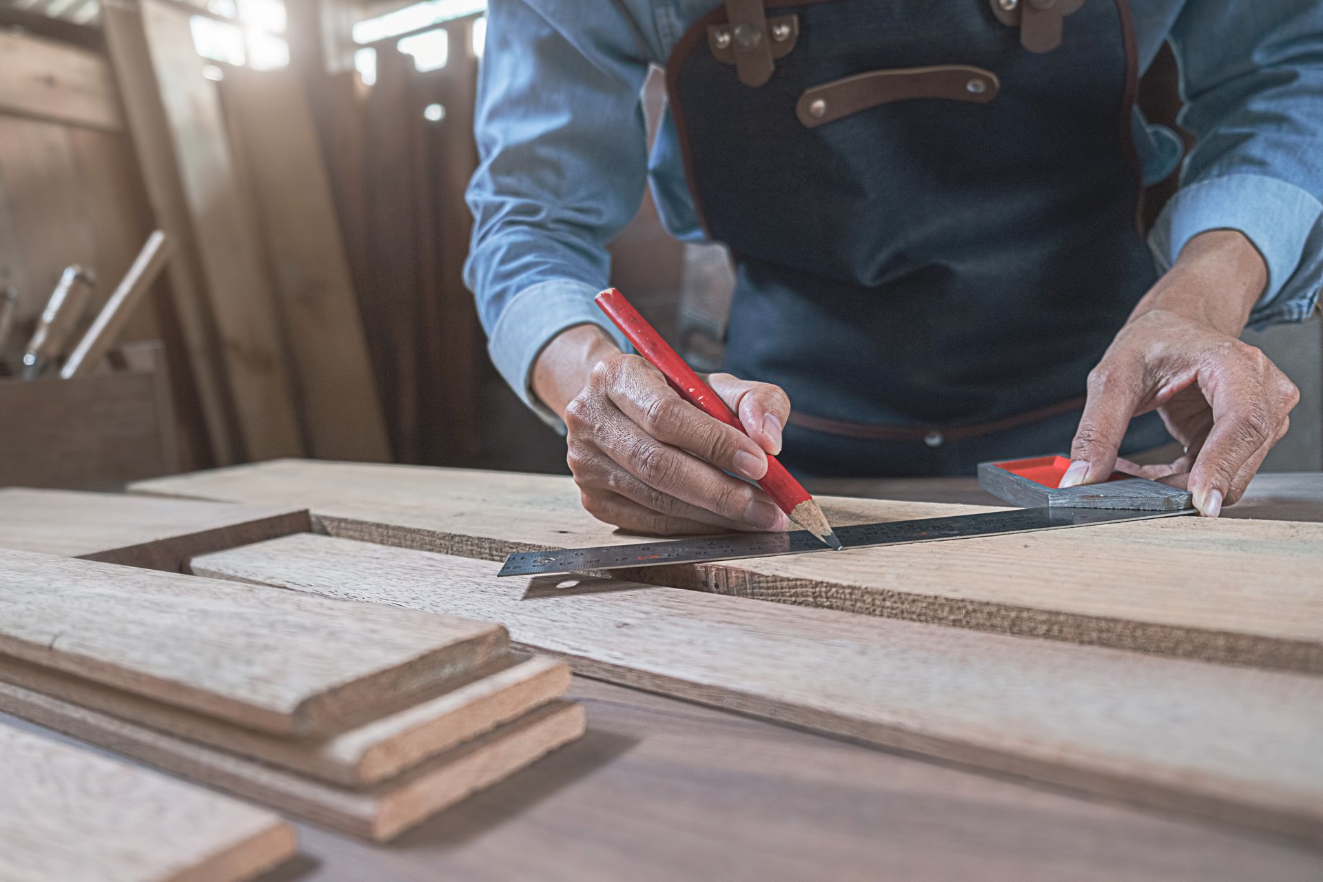 Un menuisier utilise un crayon et une équerre pour mesurer et marquer le bois dans son atelier.