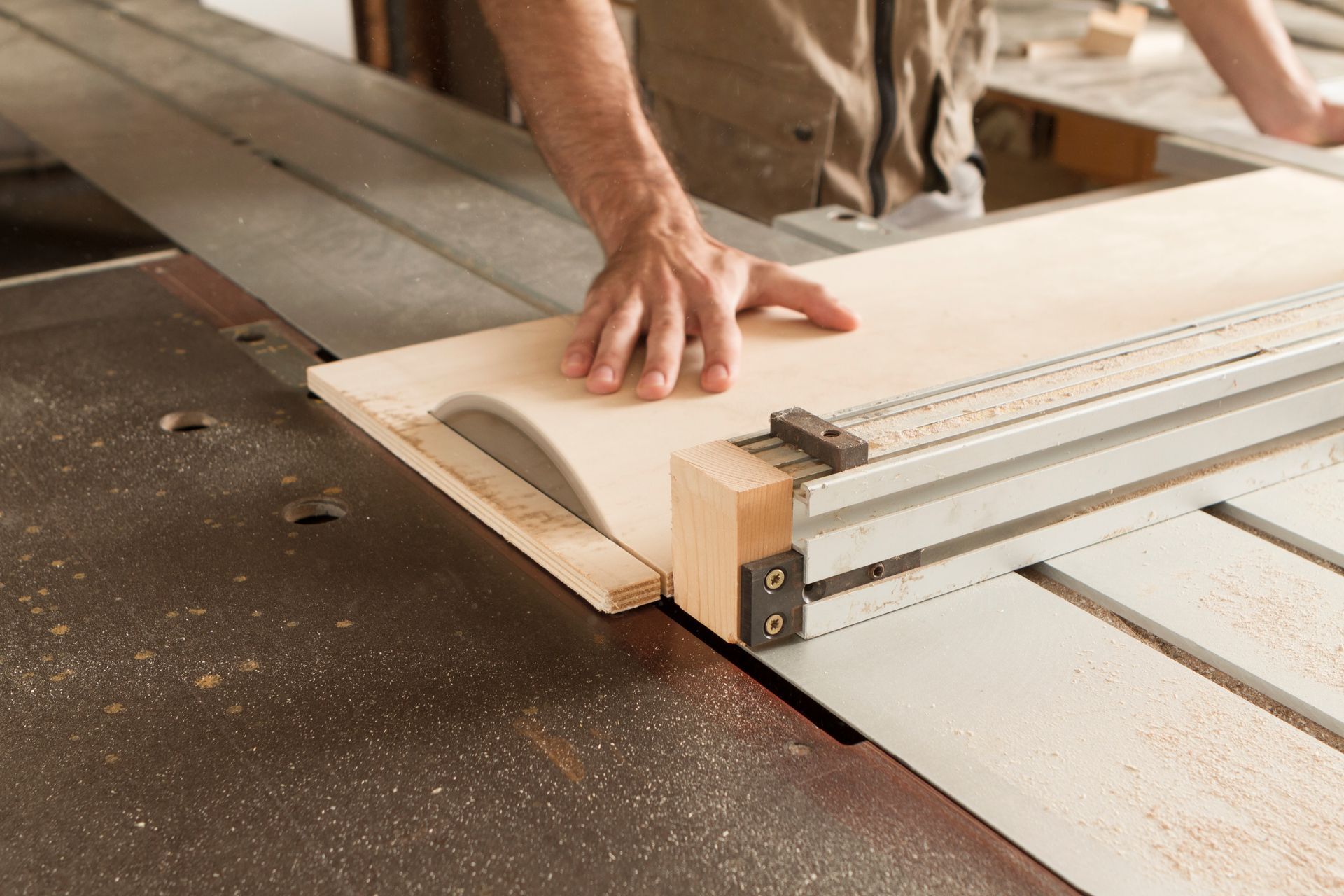 Une personne utilise une scie circulaire pour couper un morceau de bois clair dans un atelier.