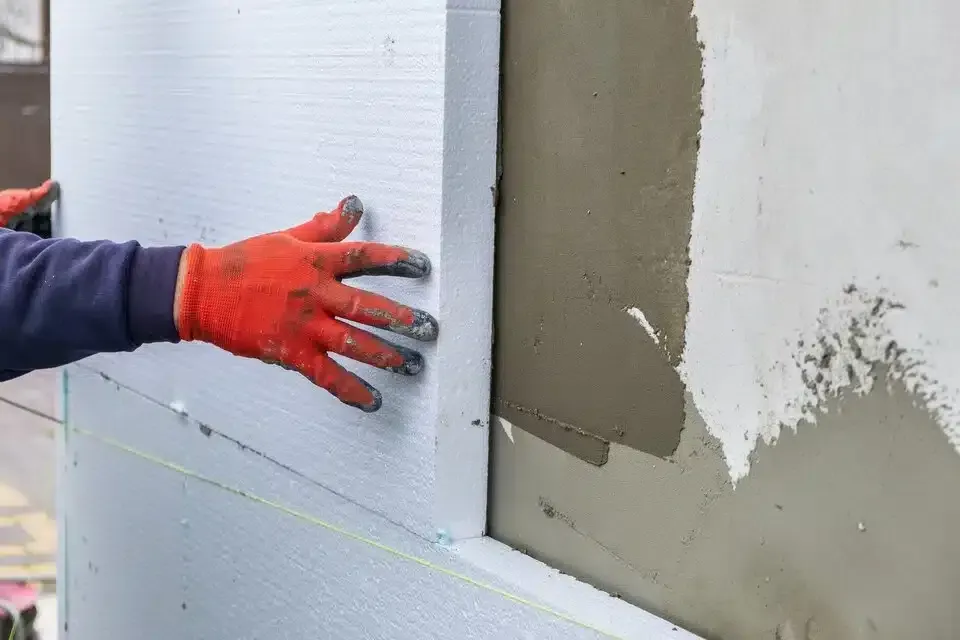 Una persona sostiene un trozo de poliestireno en una pared.
