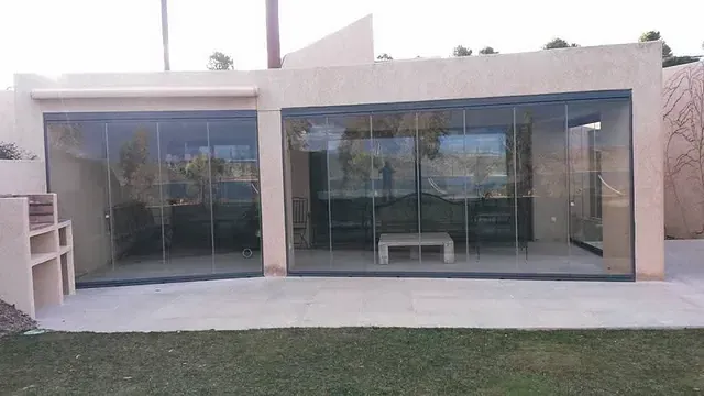 Una casa con muchas ventanas y una mesa en el patio trasero.