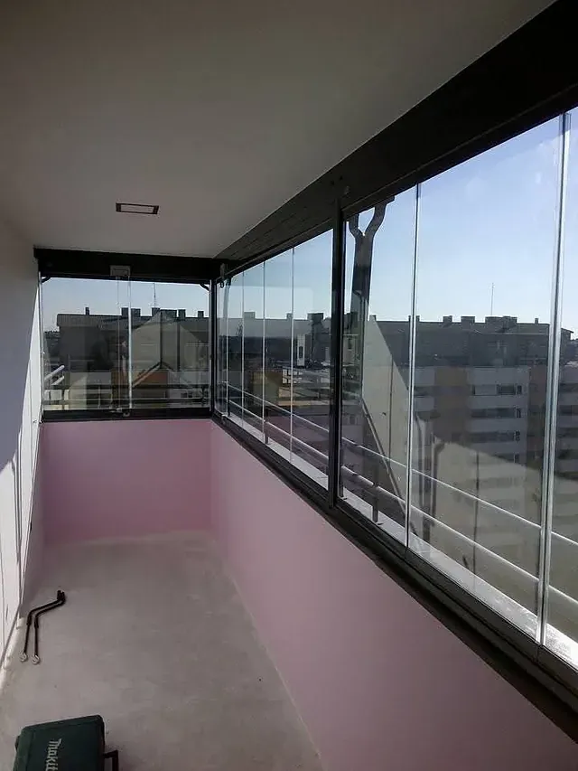 Un balcón con muchas ventanas y vista a una ciudad.