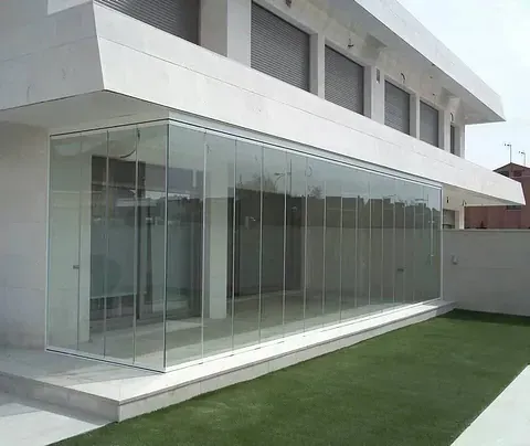 Un edificio grande con muchas ventanas y un césped delante.