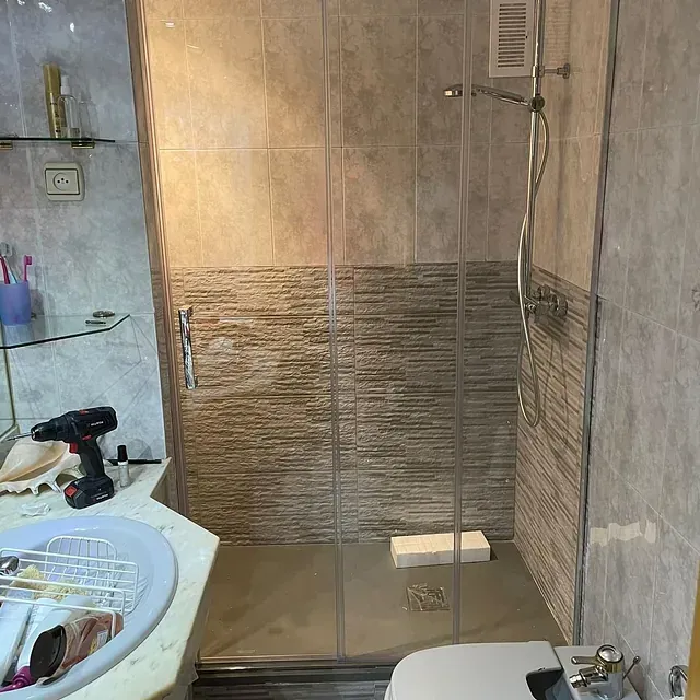 Un baño con ducha a ras de suelo y un inodoro.