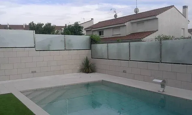 Una gran piscina está rodeada por una valla de cristal.