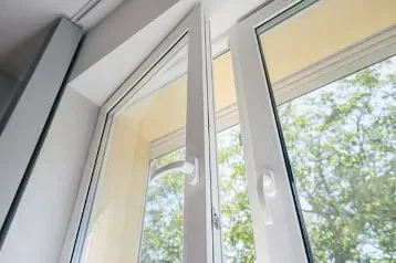 Un primer plano de una ventana abierta con árboles reflejados en ella.
