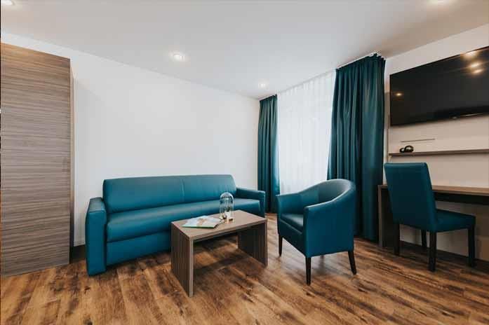 Ein Wohnzimmer mit Couch, Stühlen, Tisch und Fernseher.