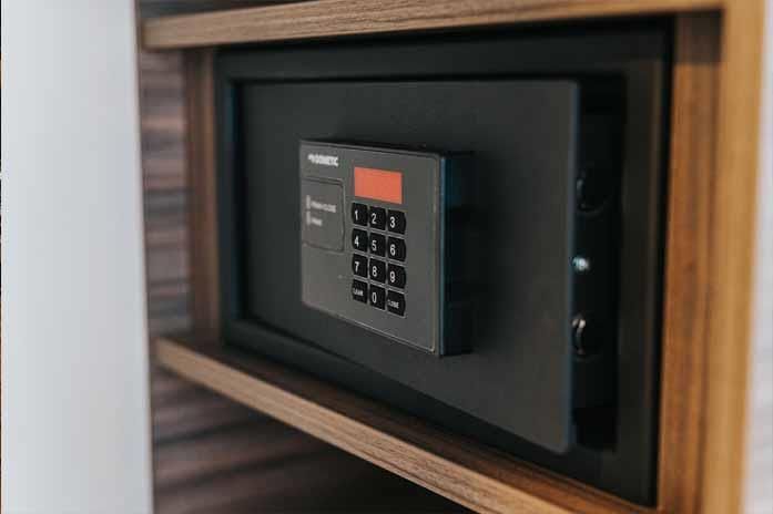 Auf einem Holzregal steht ein Hotelsafe.