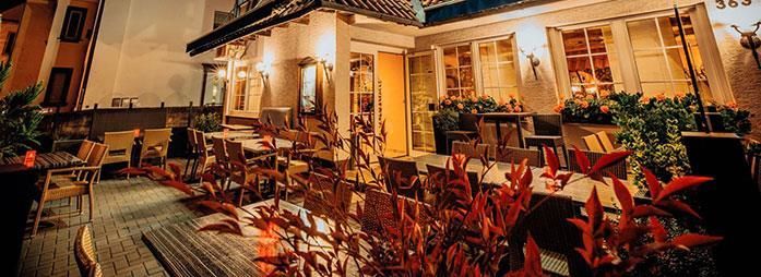 Ein Restaurant mit Tischen und Stühlen davor am Abend.