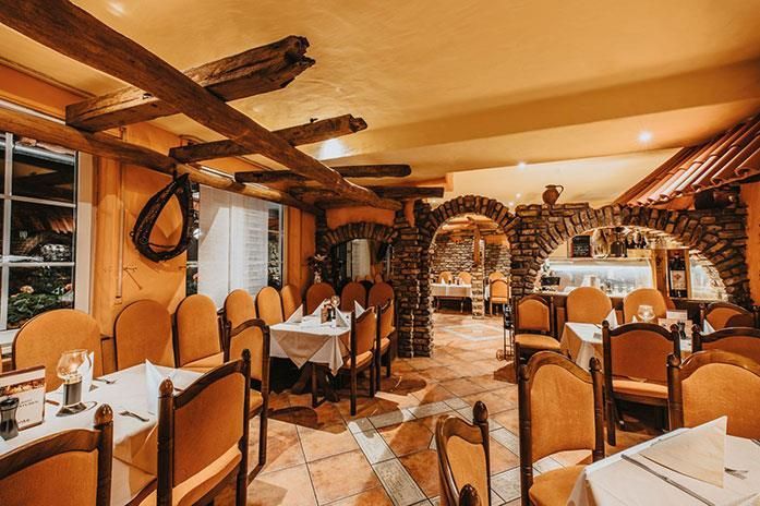 Ein Restaurant mit Tischen und Stühlen und einer Decke mit Holzbalken