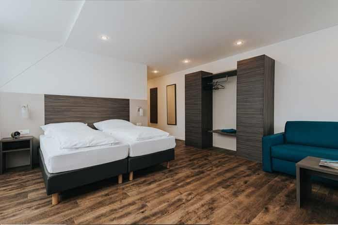 Ein Hotelzimmer mit zwei Betten und einer blauen Couch.