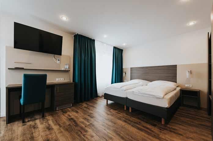 Ein Hotelzimmer mit zwei Betten, einem Schreibtisch und einem Fernseher.