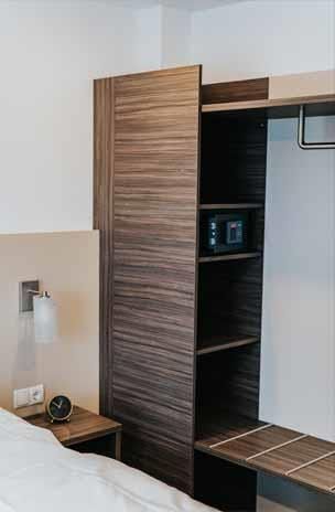 Ein Hotelzimmer mit Bett, Nachttisch, Kleiderschrank und Regal.