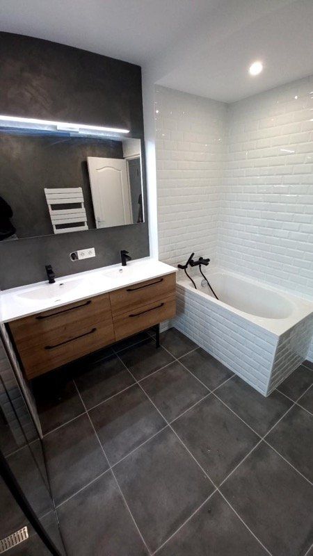 Salle de bains noire et bois avec baignoire et double vasque, robinetterie noire