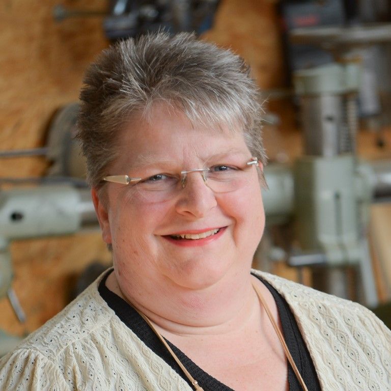 Eine Frau mit Brille und Pullover lächelt in die Kamera