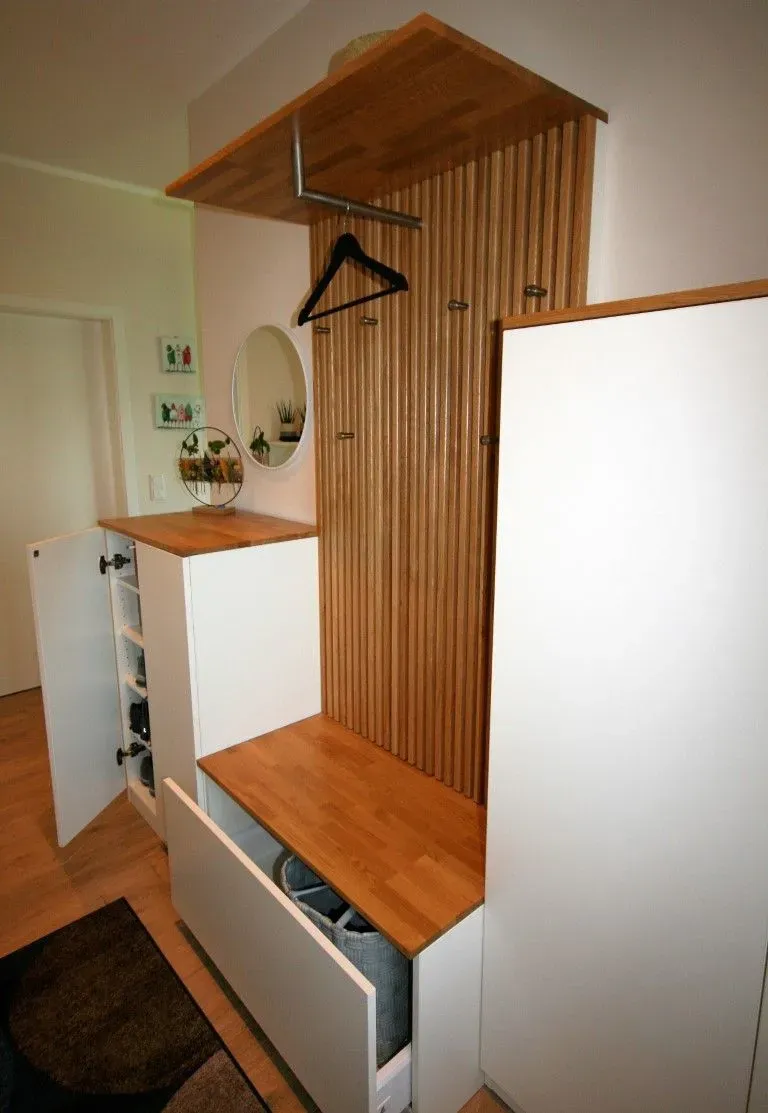 Ein Flur mit einem weißen Schrank und einer Holzbank