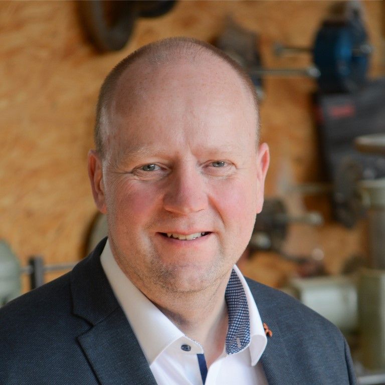 Ein Mann in Anzug und weißem Hemd lächelt in die Kamera