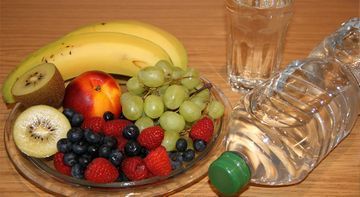 Ein Teller mit Obst und eine Flasche Wasser auf einem Tisch.