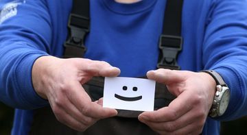 Ein Mann hält eine Karte mit einem Smiley darauf.