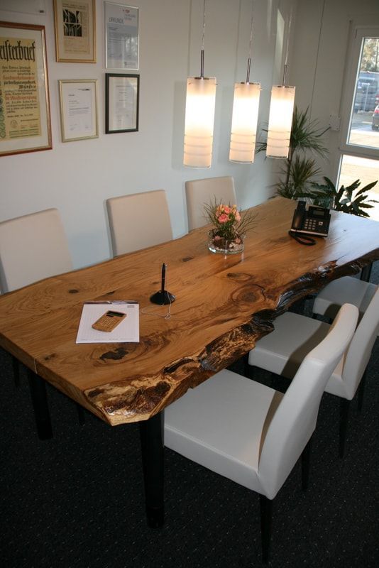 Ein langer Holztisch mit weißen Stühlen in einem Raum