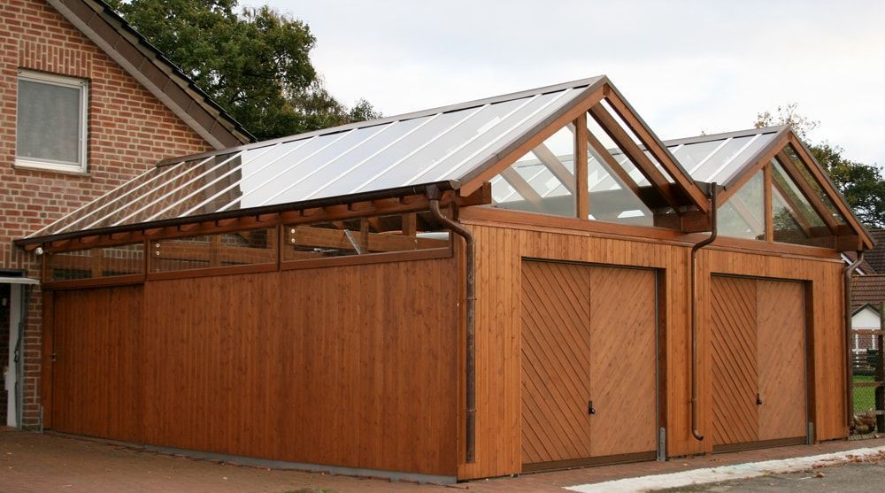 Neben einem Backsteinhaus steht eine Holzgarage mit Metalldach.