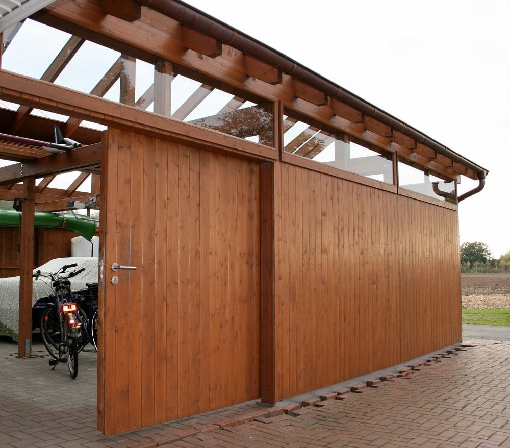 Zwei Fahrräder sind in einer Holzgarage mit Schiebetür geparkt