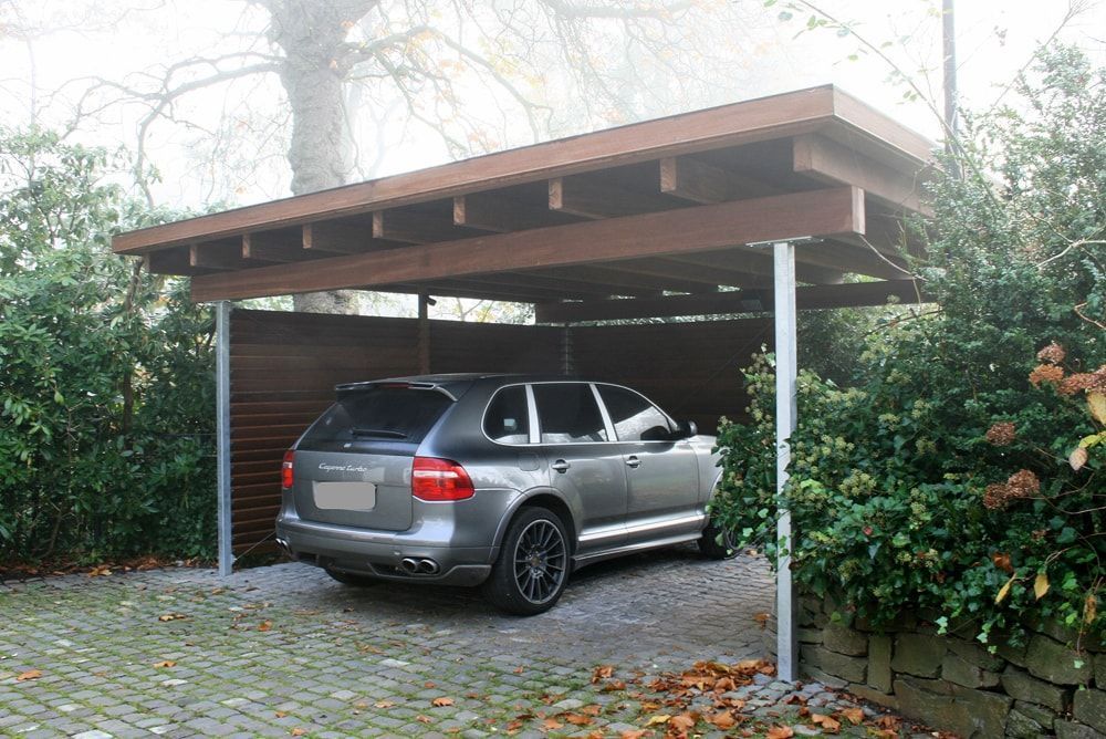 Ein Auto ist unter einem hölzernen Carport geparkt.