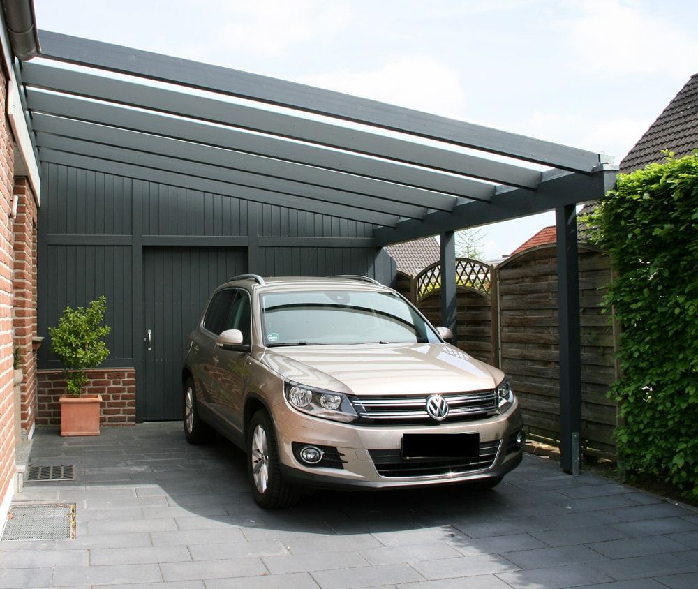 Ein Auto ist unter einem Vordach vor einem Haus geparkt.