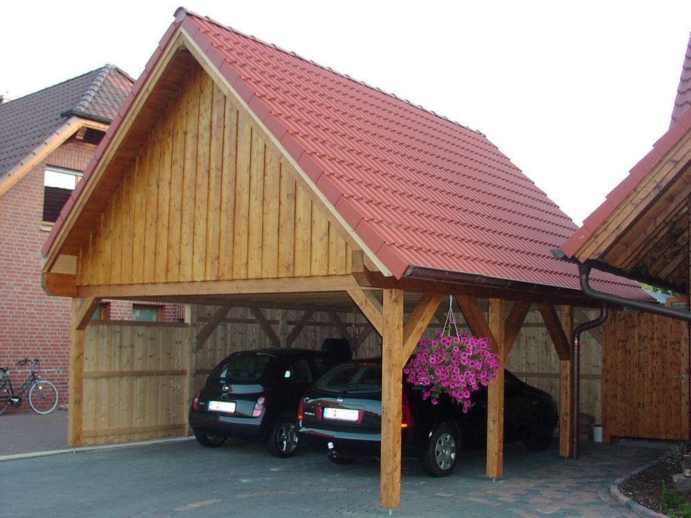 Zwei Autos sind unter einem hölzernen Carport mit einem roten Ziegeldach geparkt