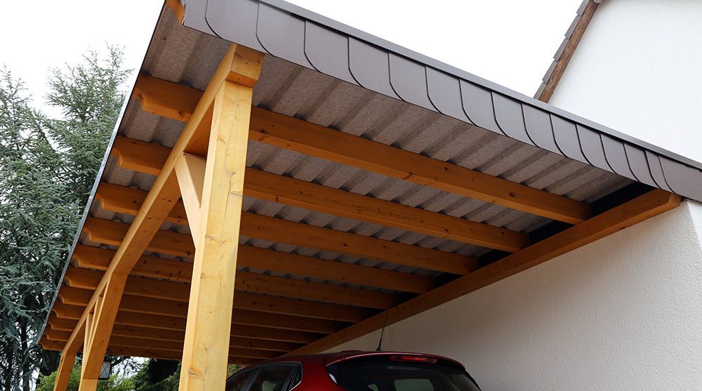 Ein Auto ist unter einem hölzernen Carport geparkt.