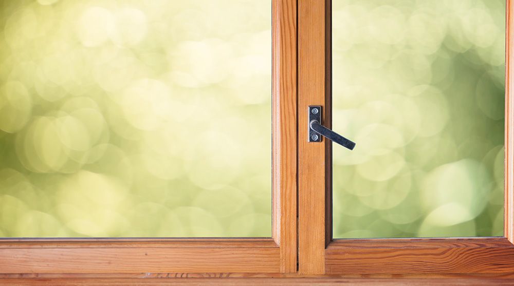 Ein Holzfenster mit einem Griff und grünem Hintergrund.